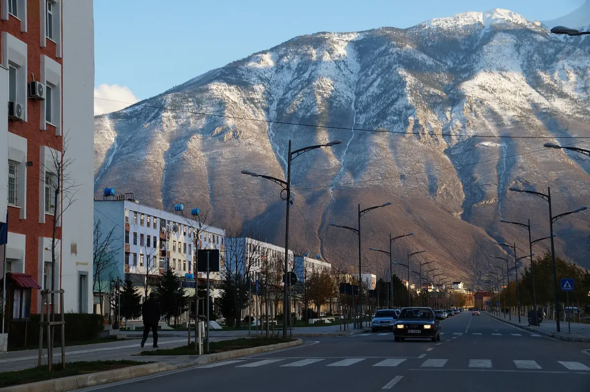A street in Kukës with snowy mountains behind